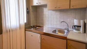 A compact kitchen with a sink, stove, and a coffee maker.