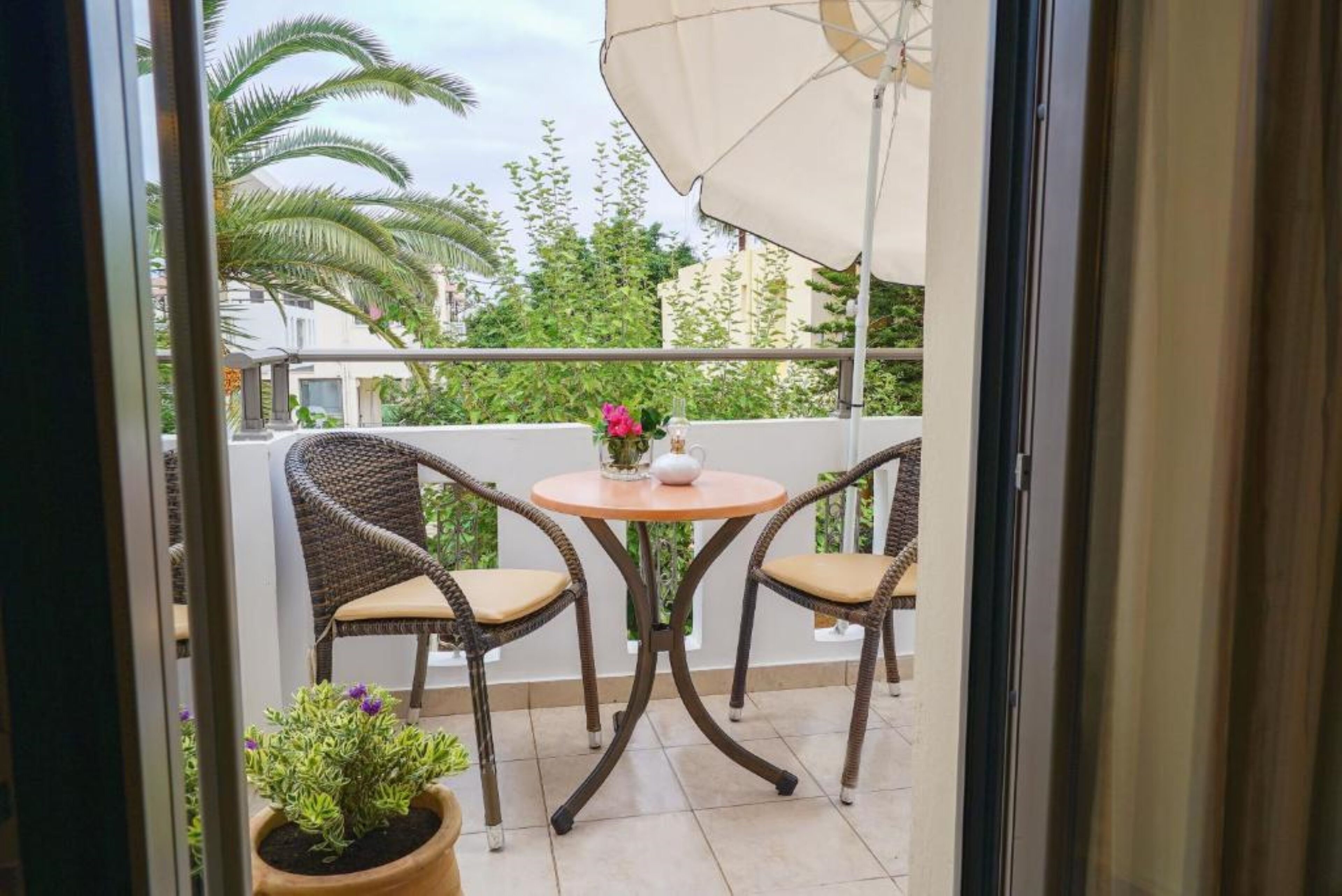 A balcony with two wicker chairs, a round table, and a potted plant.