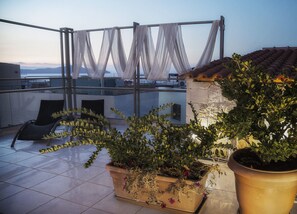 A rooftop terrace with a glass balustrade, potted plants, and a view of the sea. - Flamingos Hotel by GHH (Chania)