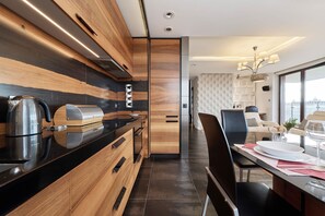 A modern kitchen with wooden cabinetry, a black countertop, and a dining area with a table set for two.