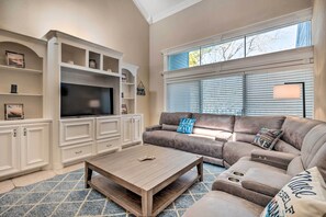 A living room with a large flat-screen TV, a brown leather sofa, and a wooden coffee table. - Idyllic Montgomery Condo w/ Pool & Lake View! (Montgomery)