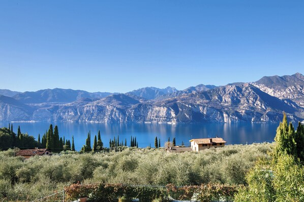 A mountainous landscape with a clear lake, a small house, and dense vegetation. - Villa Fuzzys - Old farmhouse (Malcesine)