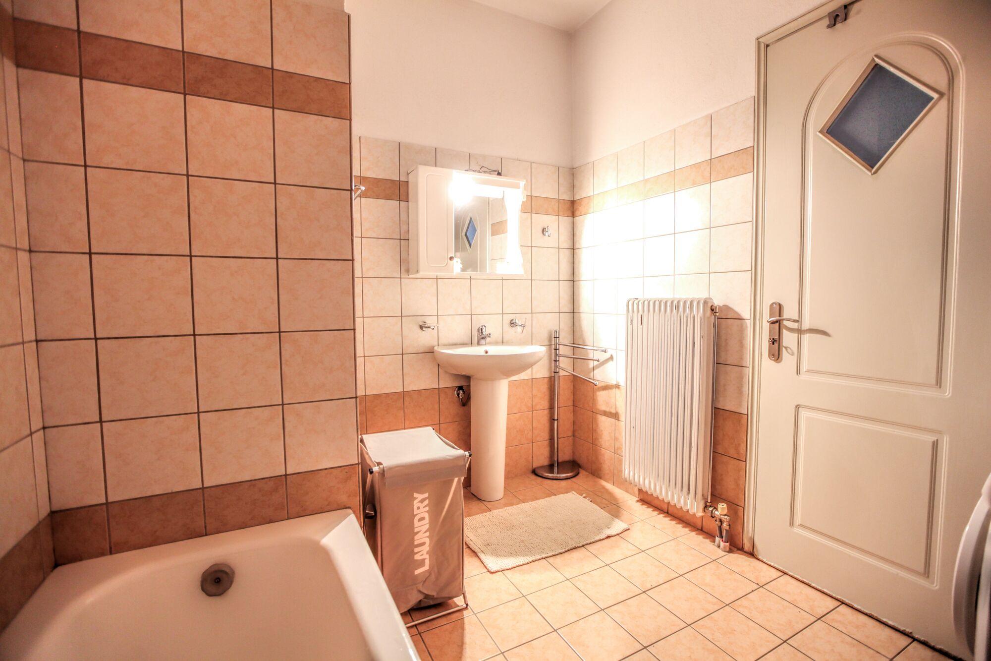 Ein Badezimmer mit Badewanne, Waschbecken und einer Tür mit Fenster.