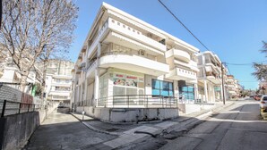 A multi-story building with a ground-floor market and upper-floor residential units. - Grand Meteora Central Luxury Apartment (Kalabaka)
