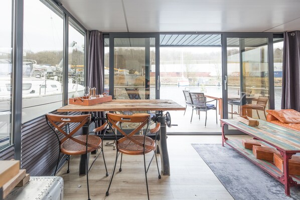 A modern interior with a dining area, large windows, and a view of a marina.