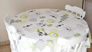 A round dining table with a floral tablecloth, surrounded by white chairs. - Gîte les palmiers (Roquebrune-sur-Argens)