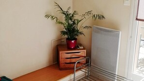 A room with a wooden bench, a potted plant, a metal chair, and a map on the wall. - Gîte les palmiers (Roquebrune-sur-Argens)