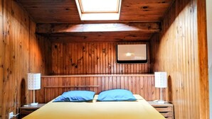 A wooden room with a bed, two bedside lamps, and a skylight. - Gîte les palmiers (Roquebrune-sur-Argens)