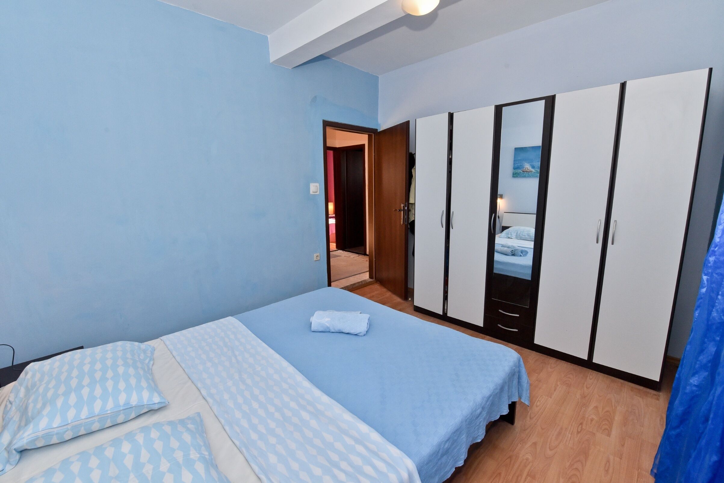 A bedroom with a bed, a wardrobe, and a door leading to another room.
