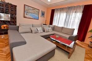 A modern living room with a large L-shaped sectional sofa, a glass coffee table, and a fireplace.