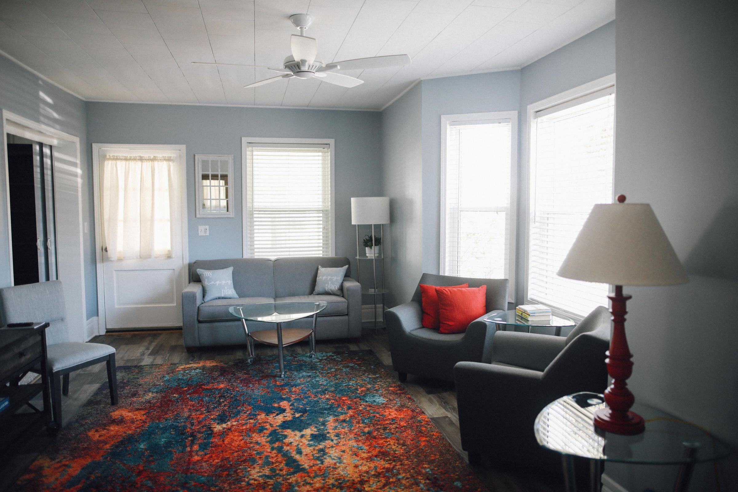 A living room with a gray sofa, a red armchair, a coffee table, and a colorful rug.