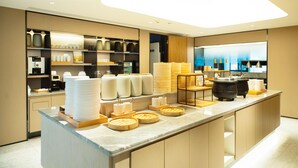 A modern kitchen area with a marble countertop, various food containers, and a coffee machine. - Ji Hotel (Chongqing)