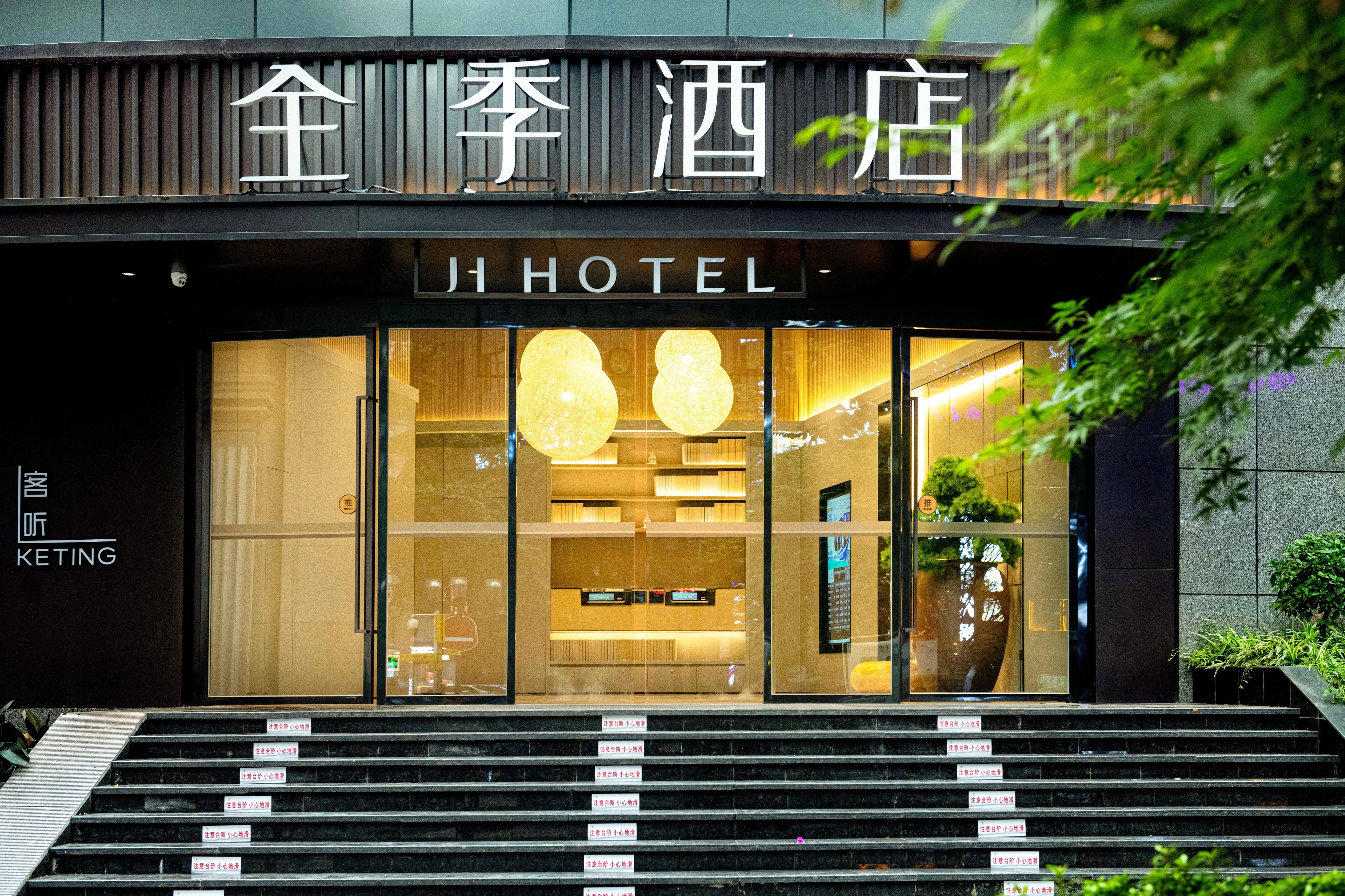 A hotel entrance with a sign reading 'JI HOTEL' and a staircase leading up to the entrance.
