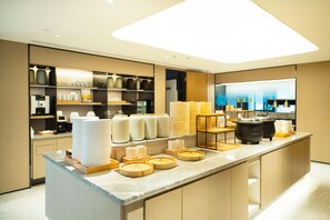 A modern kitchen area with a marble countertop, various food containers, and a coffee machine. - Ji Hotel (Chongqing)
