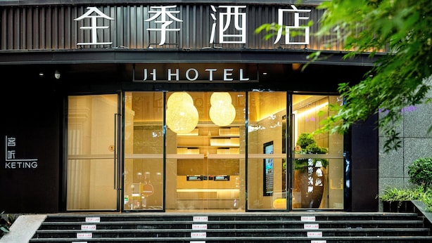 A hotel entrance with a modern design, featuring a staircase leading up to the entrance, and a sign above the door. - Ji Hotel (Chongqing)