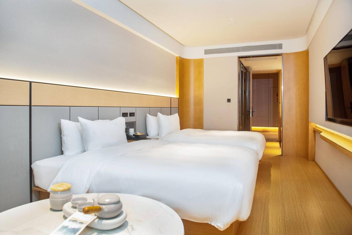 A hotel room with a large bed, bedside tables, a TV, and a bathroom door.