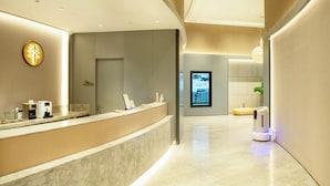 A modern reception area with a curved reception desk, a digital display, and a self-service coffee machine. - Ji Hotel (Chongqing)