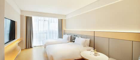 A hotel room with two beds, a desk, a round table, and a TV.