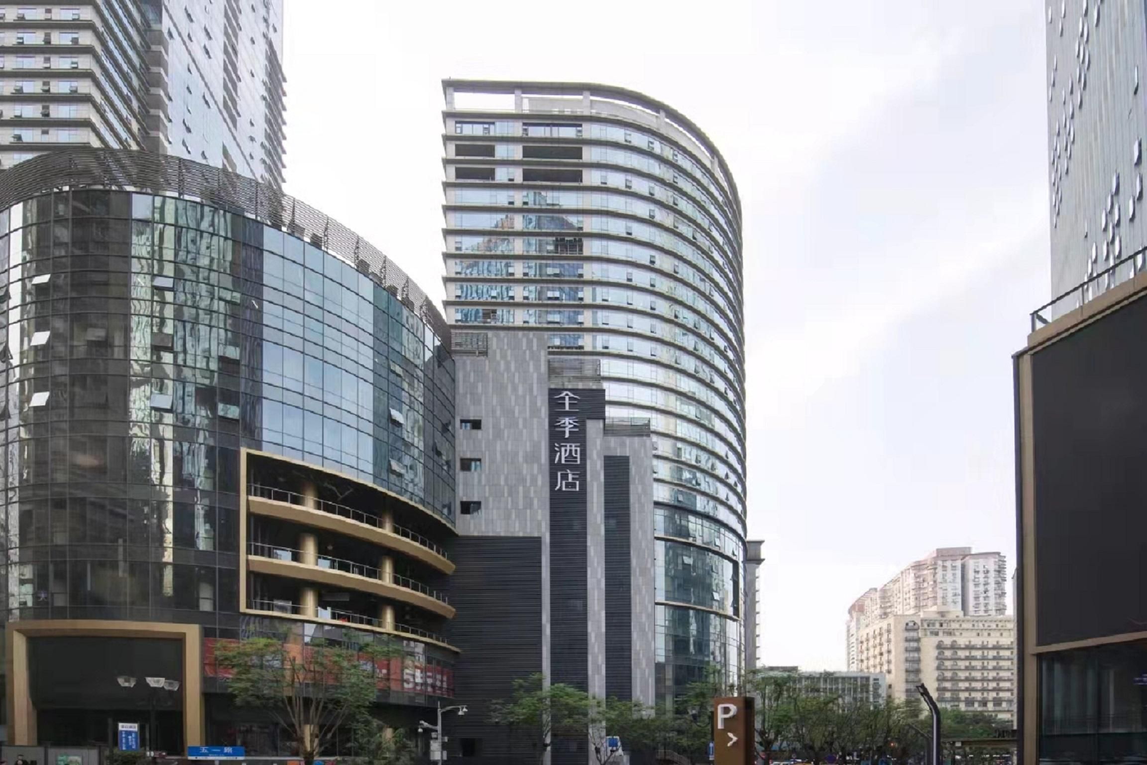 A modern hotel with a curved facade, multiple floors, and a prominent sign indicating it is a hotel.