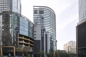 A modern building with a curved facade, multiple floors, and a prominent vertical sign. - Ji Hotel (Chongqing)