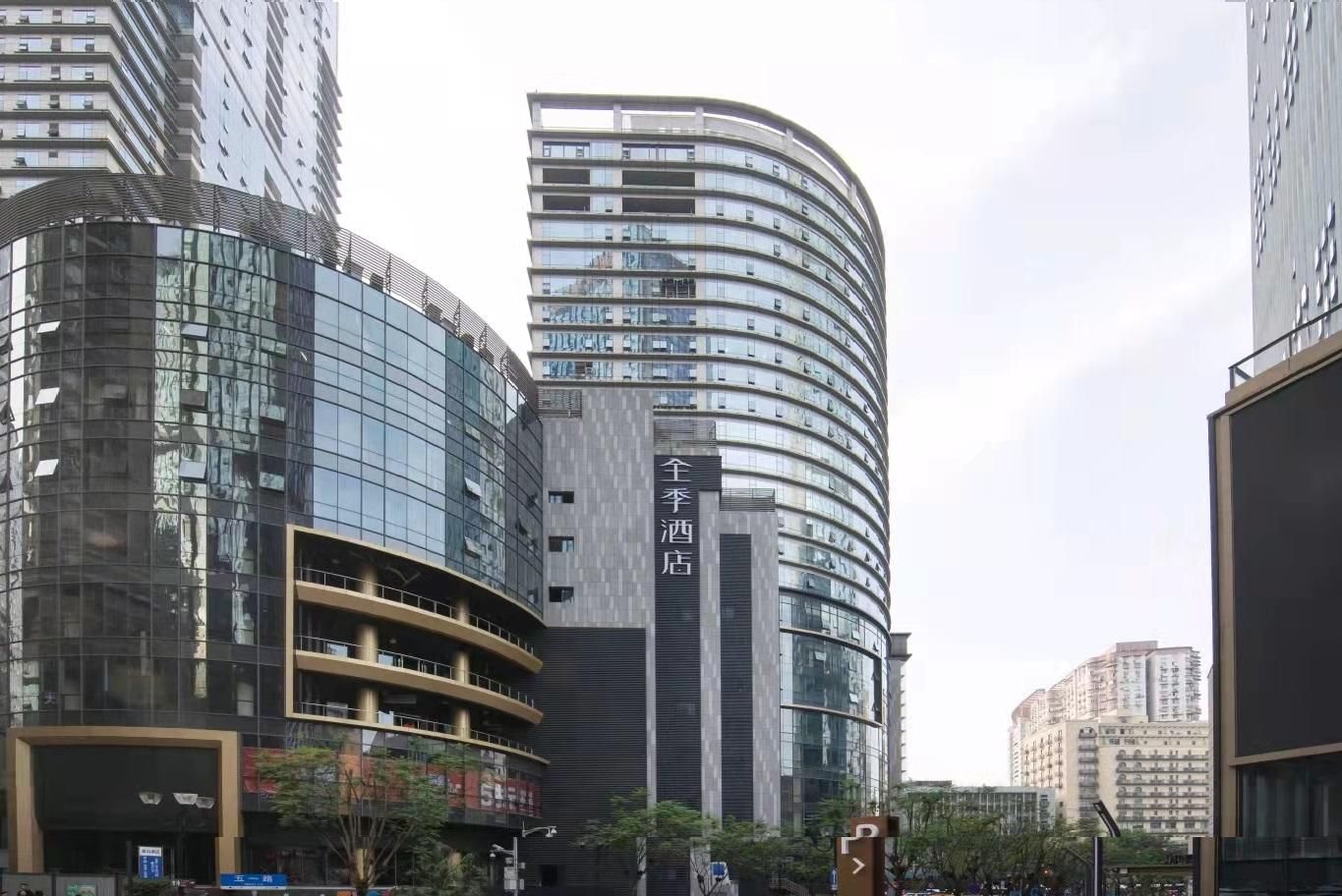 Un edificio moderno con fachadas de vidrio curvas y un letrero vertical llamativo.