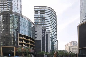 A modern hotel with a curved facade, multiple floors, and a prominent entrance. - Ji Hotel (Chongqing)