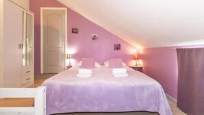 A bedroom with a bed, two bedside tables, a wardrobe, and a door. - Purple - Cosy duplex in the heart of L'Hermitage, close to the lagoon (Saint-Paul)