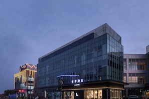 Un hôtel moderne, avec une façade en verre et une enseigne indiquant qu’il s’agit d’un hôtel.