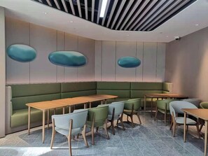 A modern interior with a curved bench seating area, wooden tables, and green upholstered chairs. - Ji Hotel Shanghai Pudong Airport Zhuqiao (Shanghai)