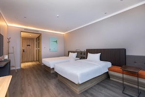 Une chambre d’hôtel avec deux lits, un bureau, une chaise et une porte donnant sur une autre pièce.