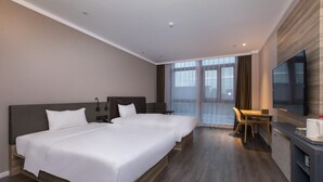 Een hotelkamer met twee bedden, een bureau, een stoel, een televisie en een groot raam.
