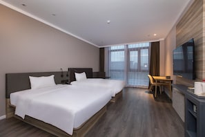 Une chambre d’hôtel avec deux lits, un bureau, une chaise, une télévision et une grande fenêtre.