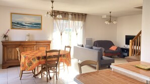 A dining area with a table and chairs, a sofa, a TV, and a staircase. - Villa with terrace and garden near the beach (Narbonne plage)