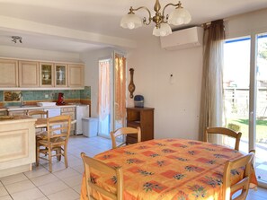 A kitchen with wooden cabinets, a dining table with a floral tablecloth, and a chandelier.