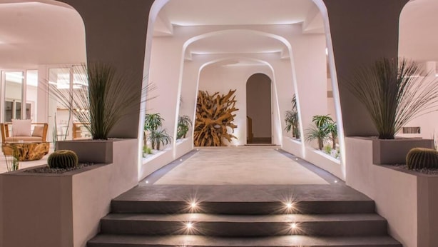 Un interior moderno con una escalera central que conduce a una habitación, flanqueada por paredes blancas y una decoración minimalista.