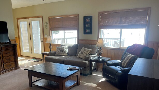 A living room with a sofa, a coffee table, a TV on a stand, and a window with blinds. - Making Memories in Red River (Red River)