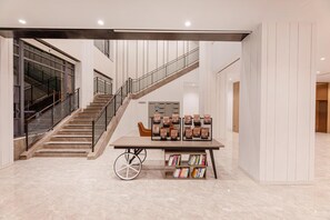 A modern interior with a staircase, a wheelchair-accessible table with books, and a row of lockers.