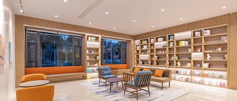 A modern library with bookshelves, seating, and a large window.