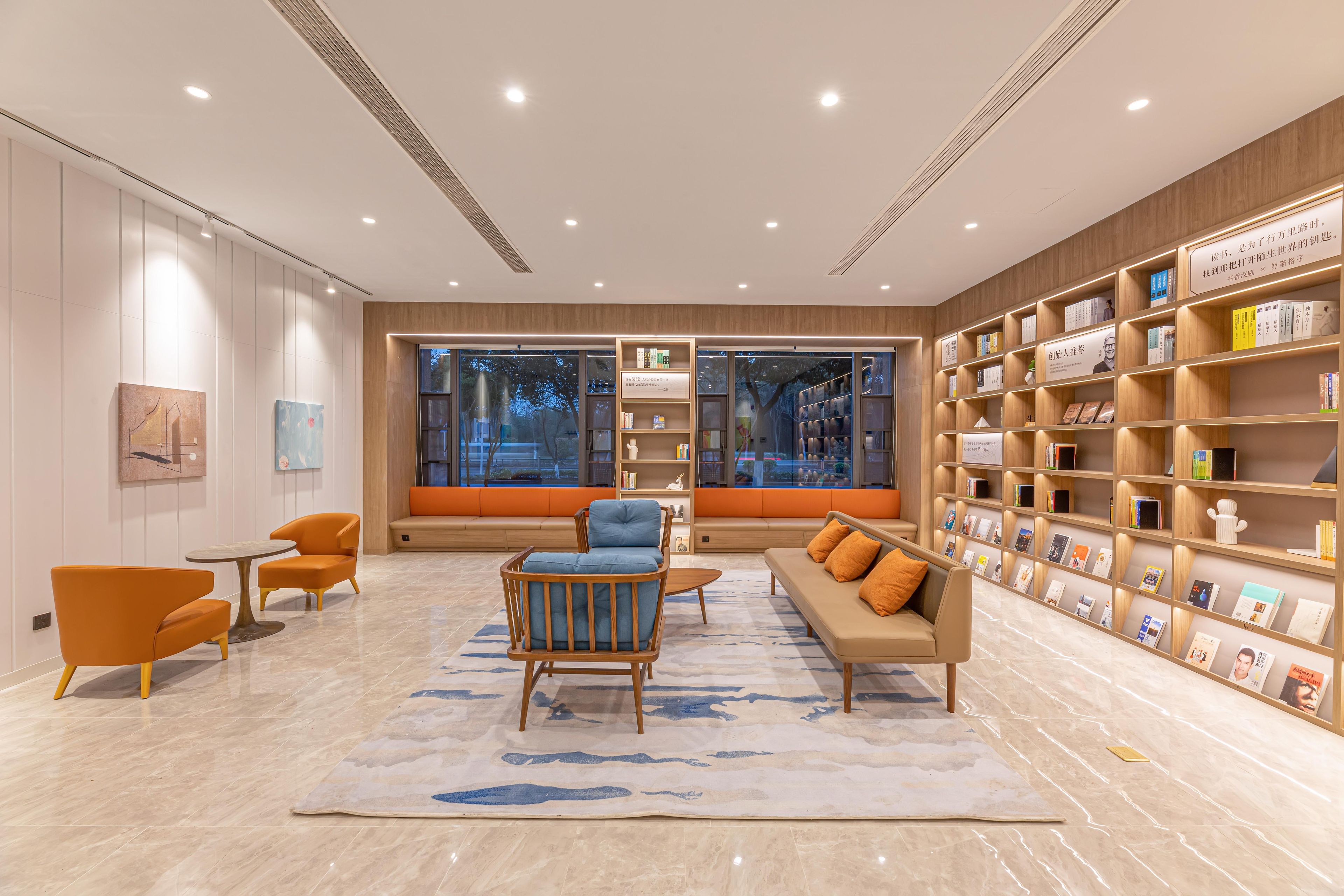 A modern interior with seating, bookshelves, and large windows.