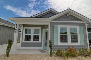 Situated on a well-maintained lawn, this house features a grey exterior with white trim and a pitched roof.