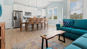 Une cuisine moderne avec des meubles blancs, des appareils en acier inoxydable et un coin repas doté de chaises en bois.