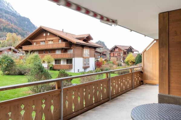 A balcony with a view of traditional wooden houses, a table, and a railing. - Chalet Apartments Iseltwald (Iseltwald)