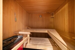 A sauna with wooden benches and a stone basin.