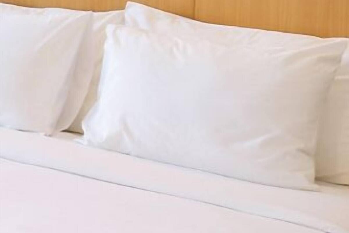 A bed with white bedding and a wooden headboard.