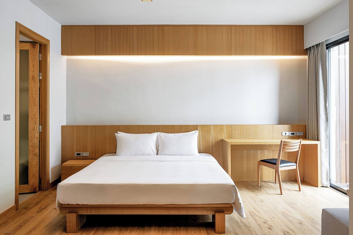 A modern hotel room with a wooden bed, a desk, and a chair.