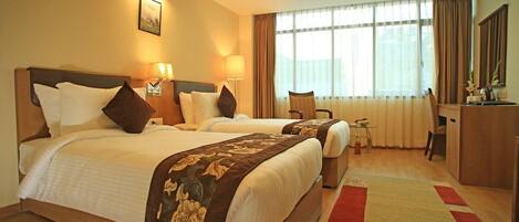 A hotel room with two beds, a desk, and a chair.
