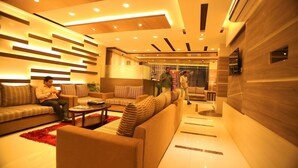 A modern hotel lobby with a sofa area, a reception desk, and a large TV screen. - Hotel Mirage Regency (Kathmandu)