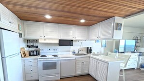 Une cuisine moderne avec des meubles blancs, un four à micro-ondes encastré, une cuisinière et un évier.