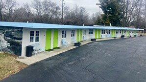 A row of motel rooms with green doors and blue awnings, each with a window and a small outdoor seating area. - Yellow Springs Motel (Yellow Springs)