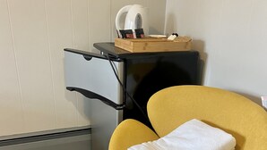 A small room with a yellow armchair, a black desk with drawers, and a white kettle on top. - Yellow Springs Motel (Yellow Springs)